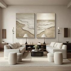 a living room filled with white furniture and two paintings on the wall above it's coffee table