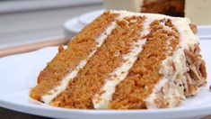 a slice of carrot cake on a white plate next to another piece of cake in the background