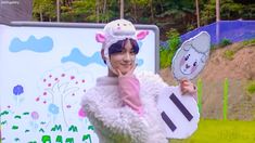 a woman in a sheep costume holding up a paper cutout with an animal on it