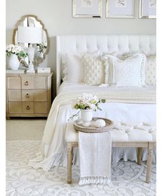 a bedroom with white furniture and pictures on the wall