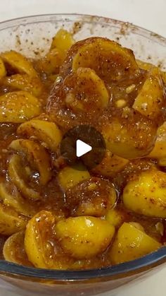 a glass bowl filled with bananas covered in brown sauce on top of a white table