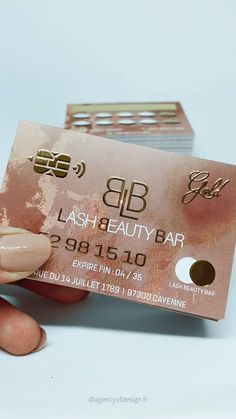 a person holding up a pink business card with gold foil on the front and bottom