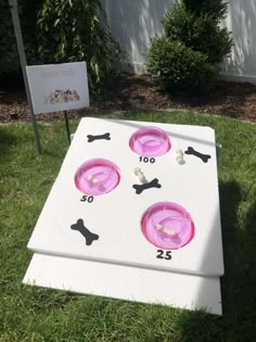 a white board with pink plates on it in the grass next to a sign that says bone toss