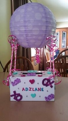 a purple balloon sitting on top of a table next to a box with pink ribbon