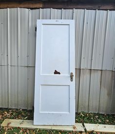 an old white door sitting in front of a metal building