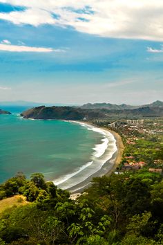 an aerial view of the beach and ocean with mountains in the backgrouund