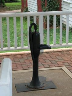 a black umbrella stand on the ground in front of a white porch with red brick walkway