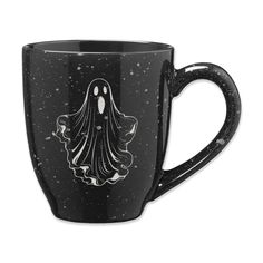 a black coffee mug with a ghost on it's side and stars in the background