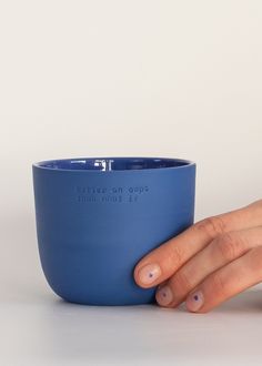 a woman's hand is holding a blue bowl