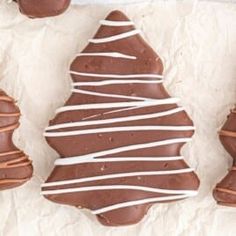 chocolate covered cookies with white icing on parchment paper and one cut in half to look like a christmas tree