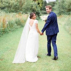 a bride and groom holding hands in the grass