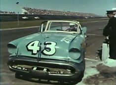 an old photo of a man standing next to a car with number 43 on it