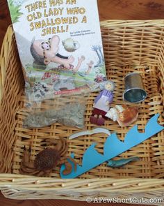 a basket filled with toys and books sitting on top of a wooden table next to a book