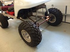 an off - road vehicle is parked in a garage with two large tires on it