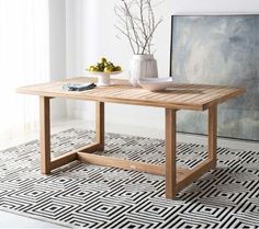 a wooden table sitting on top of a rug next to a vase filled with flowers