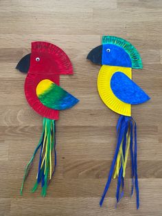 two paper plates with birds on them sitting on top of a wooden floor next to each other