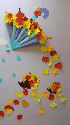 an umbrella is surrounded by fall leaves on the floor and cut out with scissors to make it look like they are falling