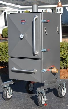 an outdoor oven sitting on wheels in front of a house