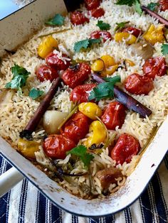 a casserole dish filled with rice, tomatoes and other vegtables