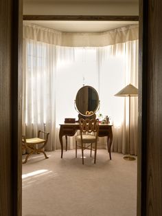 a room with a table, chair and mirror in it