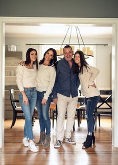 three women and one man standing in front of a dining room table