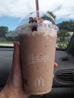 a person holding up a drink in their hand while sitting in the passenger seat of a car