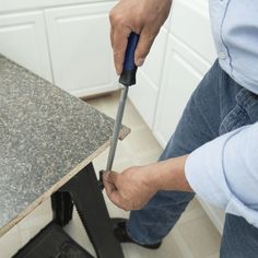 a man holding a knife in his right hand while standing next to a work bench