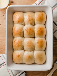 a white dish filled with rolls on top of a wooden table