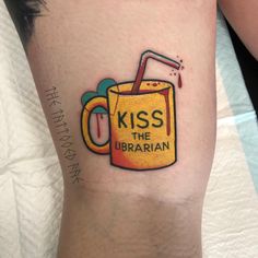 a person with a tattoo on their leg that reads kiss the librarian and has a mug in it