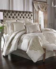 a bedroom with a large bed covered in beige and white comforters, pillows and curtains