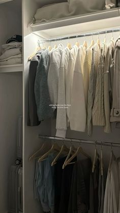 an organized closet with clothes hanging on rails