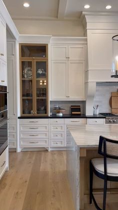 a large kitchen with white cabinets and wooden floors