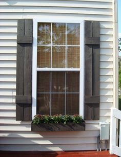 an open window with wooden shutters and flower boxes on the side of a house