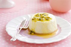 a small dessert on a plate with a fork and spoon next to it, sitting on a pink tablecloth