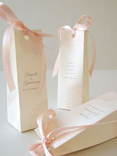 two boxes with ribbons tied around them on a white tableclothed surface, one is open and the other has a pink ribbon