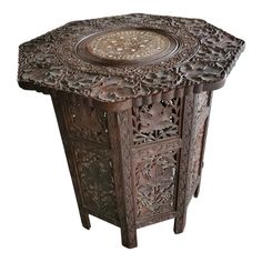 an ornate wooden table with carvings on the top and bottom, sitting against a white background