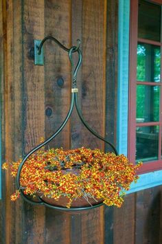 a hanging basket filled with candy corn on top of a wooden wall next to a window