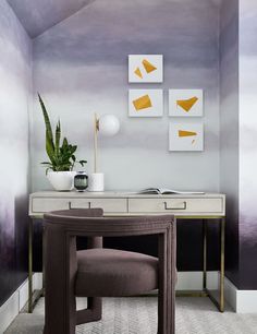 a desk with a chair, potted plant and pictures on the wall above it