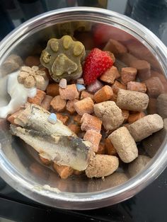 a bowl filled with different types of dog treats and strawberries on top of it