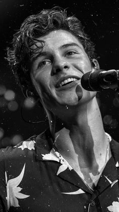 a black and white photo of a young man singing into a microphone with his mouth open