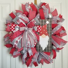 a red and silver christmas wreath with santa clause on the front, hanging on a door