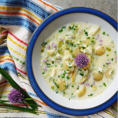 a bowl of potato and cabbage soup on a striped towel next to a flowered spoon