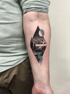 a man's arm with a mountain and lake tattoo on the left inner forearm