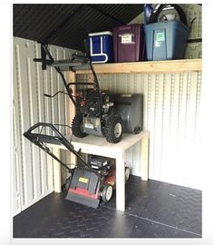 a small garage with two lawn mowers on the shelf