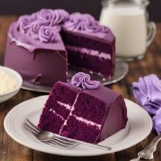 a piece of cake with purple frosting sitting on a plate next to a fork