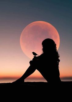 a woman sitting in front of the moon with a bird on her lap looking at it