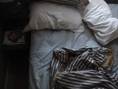 an unmade bed with blue sheets and pillows