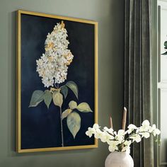 a vase filled with white flowers sitting next to a painting on a window sill