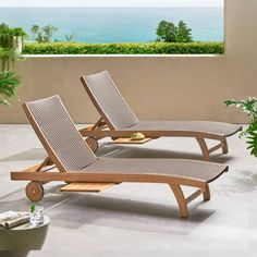 two lounge chairs sitting on top of a patio next to a potted plant and an ocean view