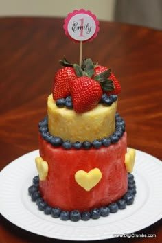 a three tiered cake with strawberries and blueberries on top